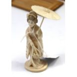 An early 20th century carved ivory Japanese female figure holding a parasol, 4¾” high.