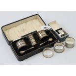 A George V silver three-piece condiment set, Birmingham 1924, cased; & four silver napkin rings.
