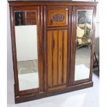 An Edwardian walnut wardrobe with moulded cornice, having fitted interior enclosed by carved panel