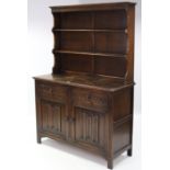 A reproduction oak dresser the upper part with two open shelves, the base fitted two frieze