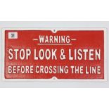 A reproduction painted cast-iron rectangular sign “WARNING STOP LOOK & LISTEN BEFORE CROSSING THE