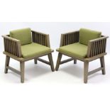 A pair of oak-frame square easy chairs with padded seats & backs upholstered green material, & on