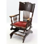 An early 20th century American carved beech spindle-back small rocking chair with spring mechanism.