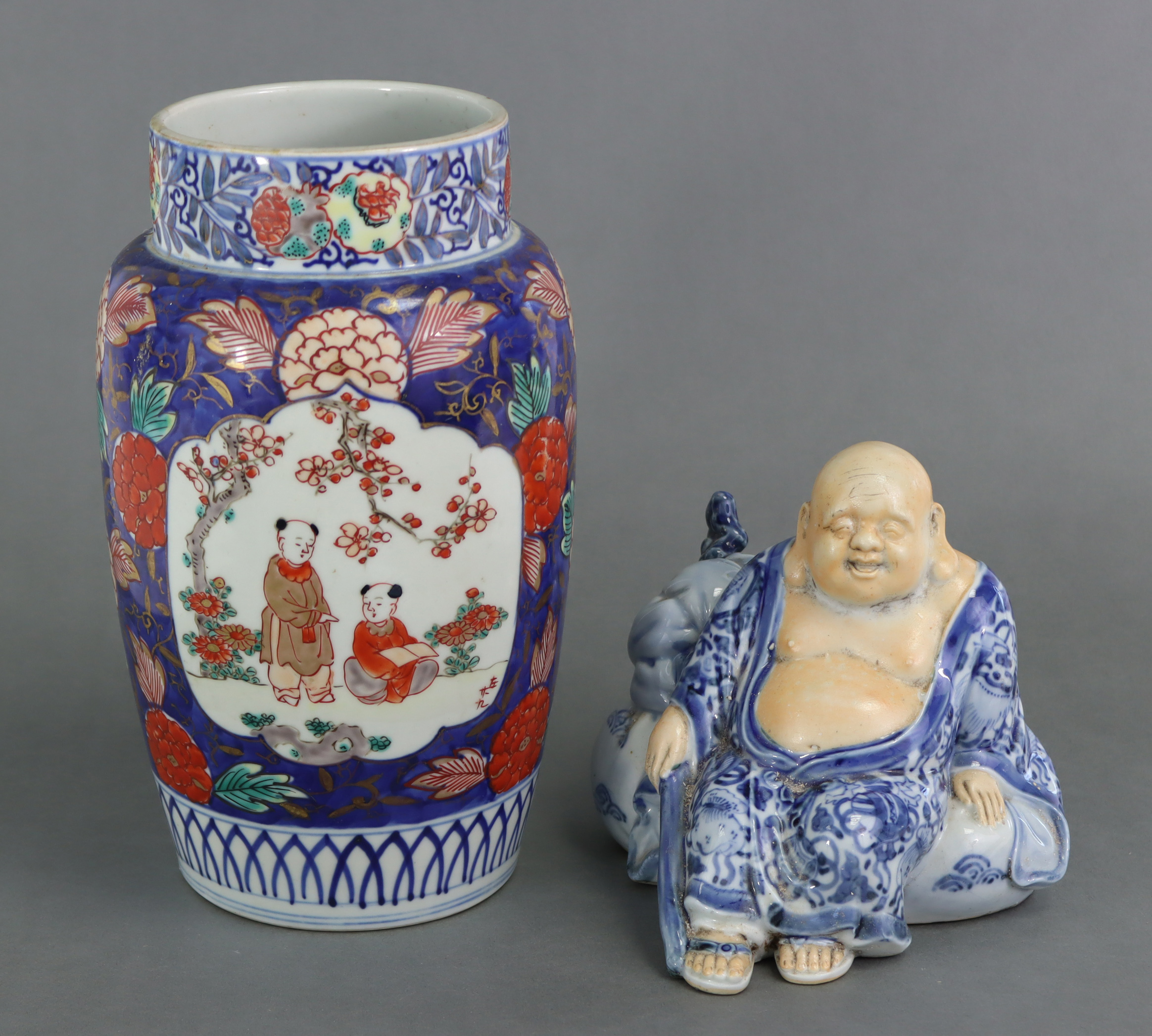 A Japanese Imari cylindrical vase, decorated with boys beside blossoming trees in reserves on a blue