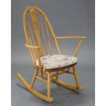 An Ercol light elm rocking chair with pierced swan design to back, with hard seat, & on round
