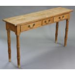 A narrow pine side table with plain rectangular top, fitted three frieze drawers, on bamboo-style