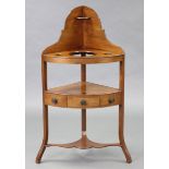 An early 19th century mahogany corner washstand, the tall shaped back with small shelf, the