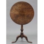 A late 18th century oak tripod table, with circular tilt-top on vase-turned centre column &