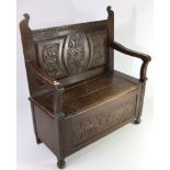A late Victorian carved oak hall bench, with open scroll arms & box seat enclosed by hinged lift-
