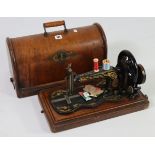 A Singer hand sewing machine in dome-top carrying case, 18” wide x 12” high.