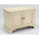 A white-finish dwarf cabinet, enclosed by pair of panel doors & on bracket feet, 34¾” wide x 24”