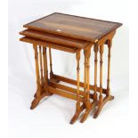 A reproduction yew wood nest of three rectangular occasional tables, each table on four spider-