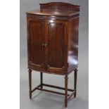 An Edwardian mahogany bow-front music cabinet, the raised back & fluted frieze with carved rosettes,