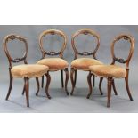 A set of four Victorian carved walnut balloon-back dining chairs with pierced centre rails, padded