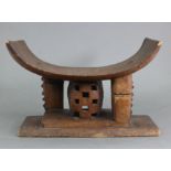 A West African carved wooden tribal stool, Ashanti, Ghana, with curved rectangular seat on pierced