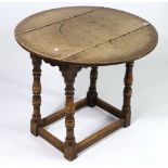 A 17th century-style joined oak small drop-leaf table with shaped apron & on turned supports, 26”