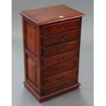 A mahogany small upright chest fitted seven long drawers with brass swing handles, & on shaped