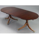 A regency-style mahogany twin-pedestal extending dining table, the crossbanded top with rounded