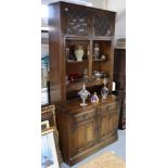 A tall oak side cabinet, the upper part enclosed by pair of glazed doors to the top with open