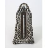 A late Victorian desk thermometer in silver embossed frame; & an easel support, 7” high, Chester
