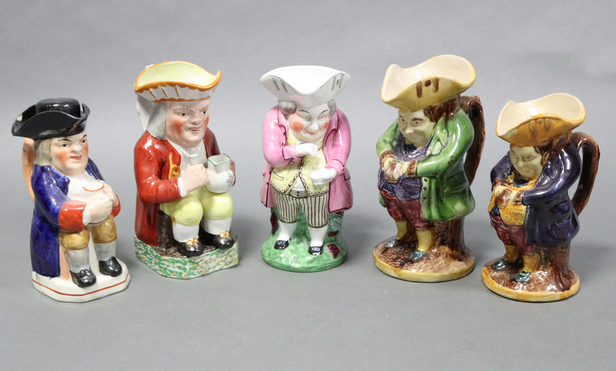 A collection of five Victorian Staffordshire pottery Toby jugs, three standing & two seated, the