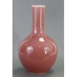 A CHINESE PORCELAIN ‘PEACHBLOOM’ GLAZED BOTTLE VASE with tall narrow cylindrical neck, 10½” high;