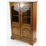 A reproduction oak side cabinet with two adjustable shelves enclosed by pair of glazed doors with
