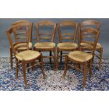 A set of six late 19th century provincial dining chairs with shaped ladder backs, rush seats, & on
