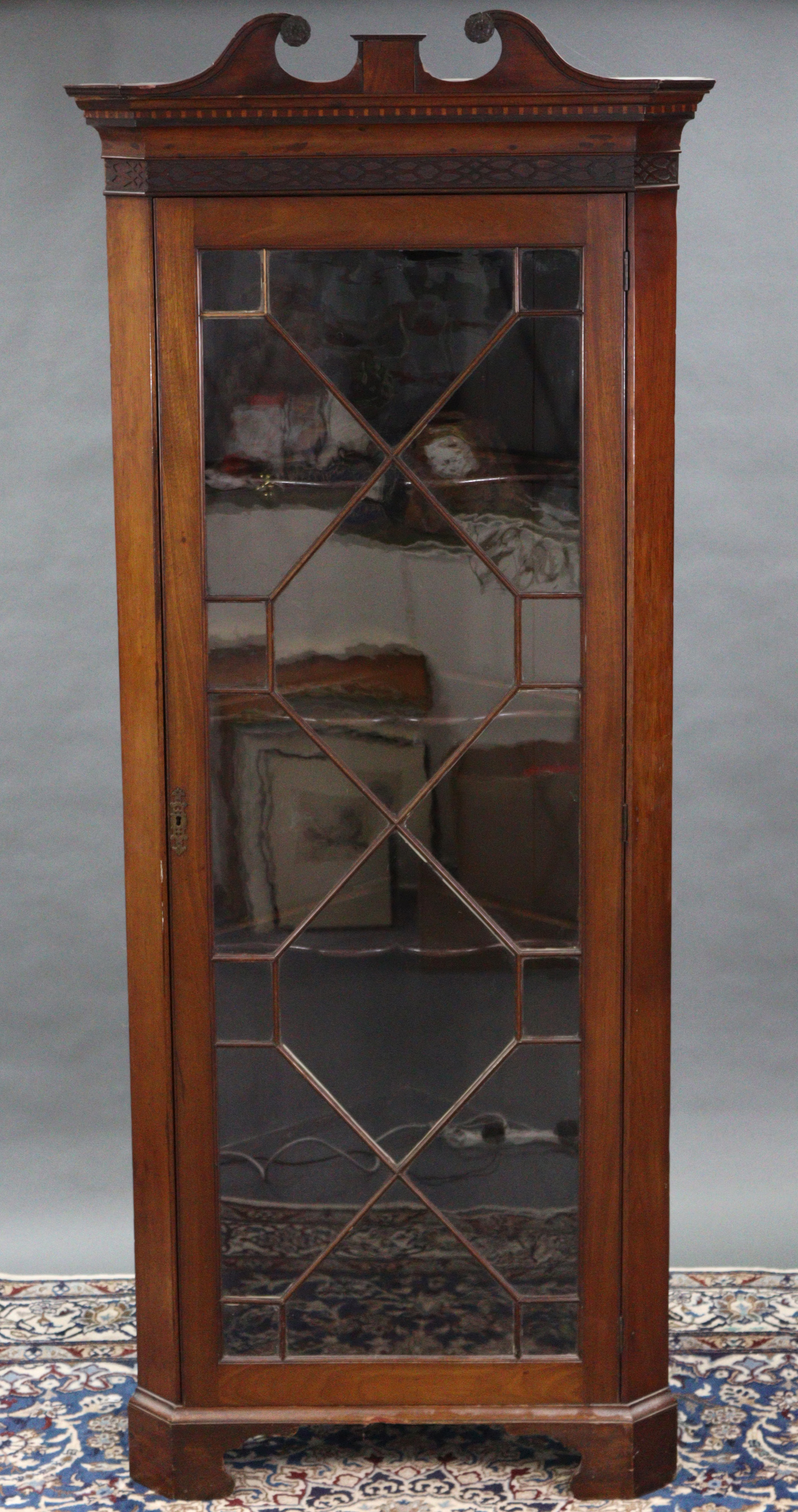 A 19th century mahogany standing corner cabinet, with broken-arch swan-neck cornice above