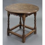 A 17th century-style oak occasional table with circular top, carved frieze, & on four turned legs