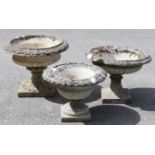 Three reconstituted stone shallow circular fluted garden urns, each on square pedestal base; 25”