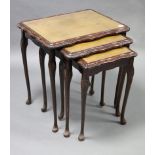 A reproduction carved mahogany nest of three rectangular occasional tables, each table inset gilt-