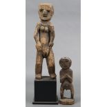 Two Burmese(?) carved wooden fertility figures, one on ebonised plinth base, 30”, & 14” high.