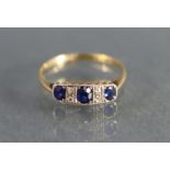 A sapphire & diamond ring, the three graduated oval-cut sapphires with pairs of small diamonds in