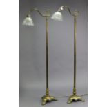 A pair of Edwardian-style brass standard lamps, each with scroll-arm light bracket & glass shade, on