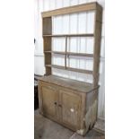 A Victorian pine dresser with open shelves above, the base fitted centre shelf enclosed by pair of