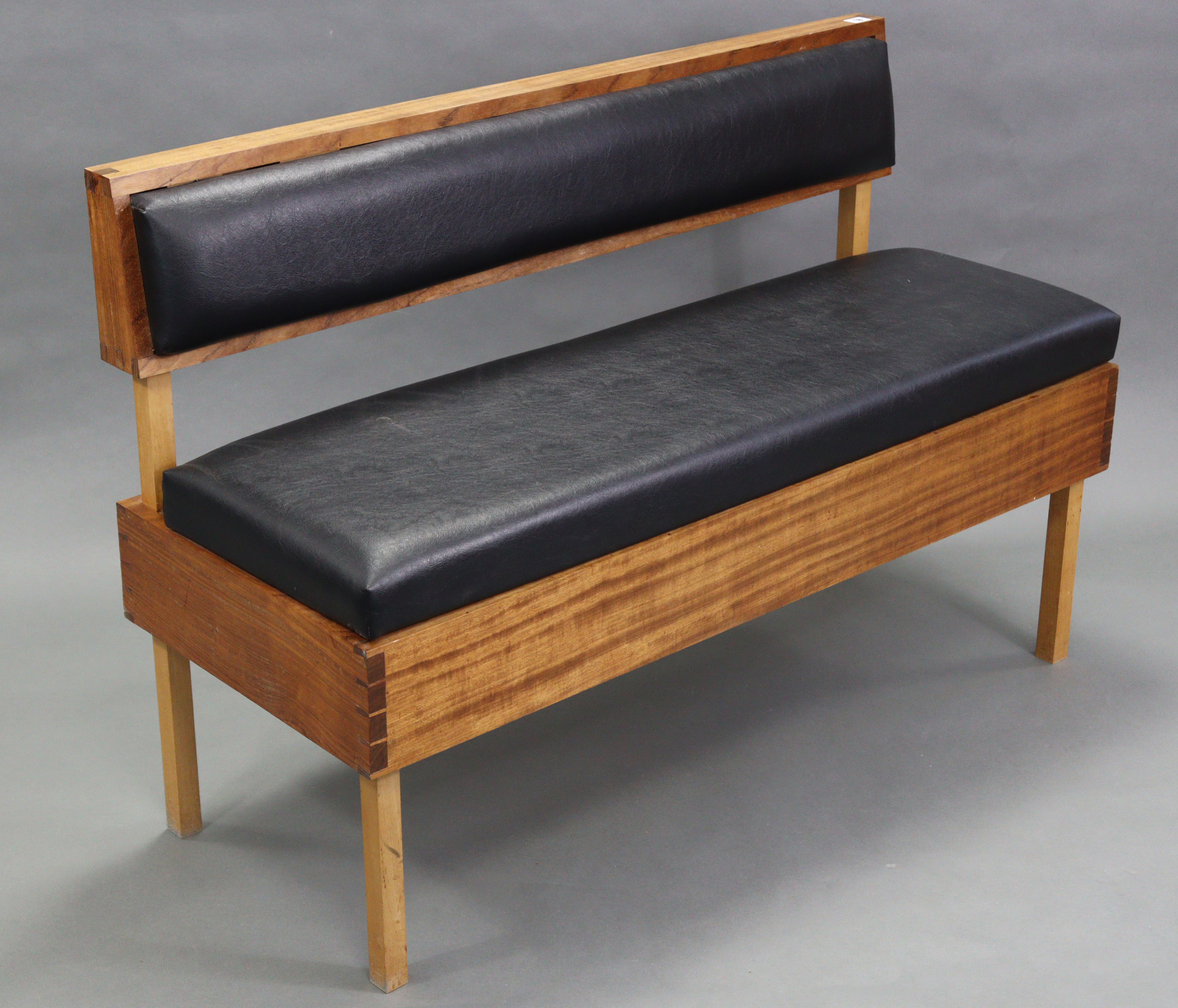 A hardwood box-seat settle, with upholstered black leather cushions set to the back & hinged seat,