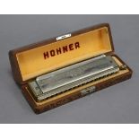 An M. HOHNER “The 64 CHROMONICA” harmonica in painted wooden fitted case, 7” wide.