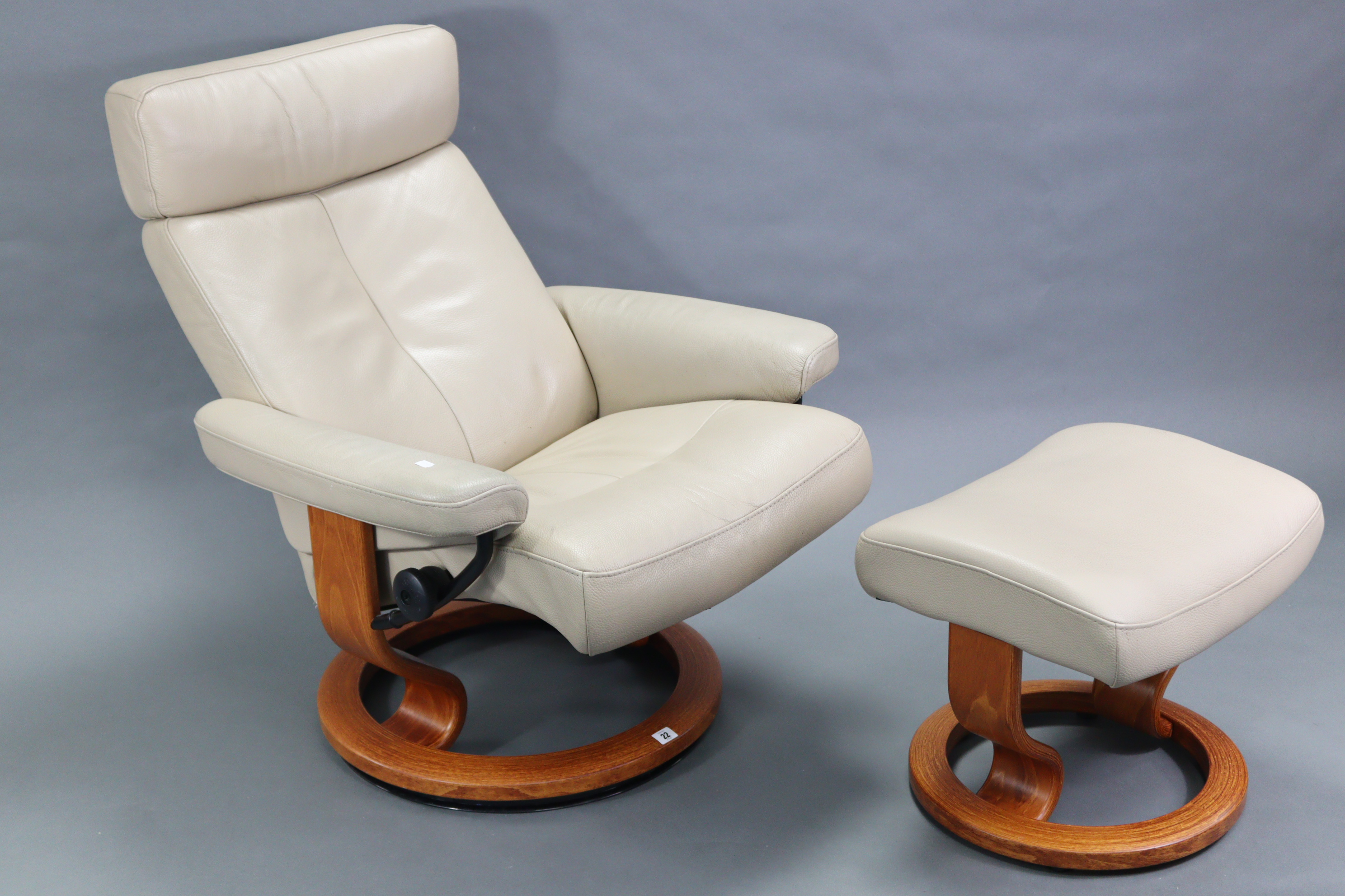 An Ekorness “Stressless” reclining swivel armchair & matching foot stool,upholstered cream leather.