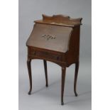 A mid-20th century oak upright bureau with carved motif to the fall front, above a single frieze