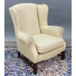 A reproduction wing-back armchair, upholstered yellow fabric, & on short square legs joined by H-