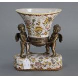 A Toussi Court flared oval vase supported by two gilt-brass cherubs, on rectangular ceramic base,