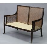 A mahogany two seater bergere settee in the late George III style, with moulded edges, turned arm