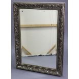 A rectangular bevelled wall mirror in silvered stylised foliate frame, 42½” x 31” over-all.