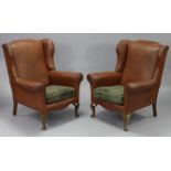 A pair of early-mid 20th century swing-back armchairs, upholstered tan leather with brass-studded
