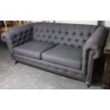 A modern Chesterfield sofa upholstered buttoned blue material, on turned legs with brass castors.