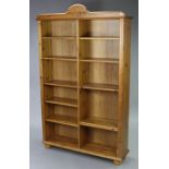 A pine open bookcase with shaped cornice, fitted ten adjustable shelves, on bun feet, 46” wide x 74”