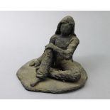 A contemporary ceramic sculpture depicting a seated figure with shoulder-length hair & crossed legs,