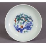 A Chinese porcelain saucer dish decorated in Doucai enamels with two encircling dragons chasing