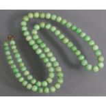 A jade necklace of eighty-four graduated spherical beads of mottled green & white colour; 28” long.
